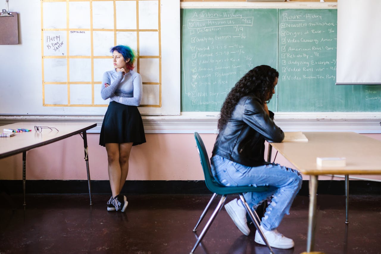 Two students in a classroom setting with a chalkboard, highlighting diversity and education.